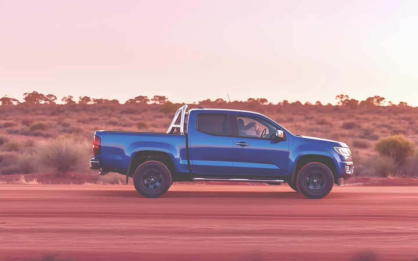 Blue dual cab ute on a red dirt track at golden hour